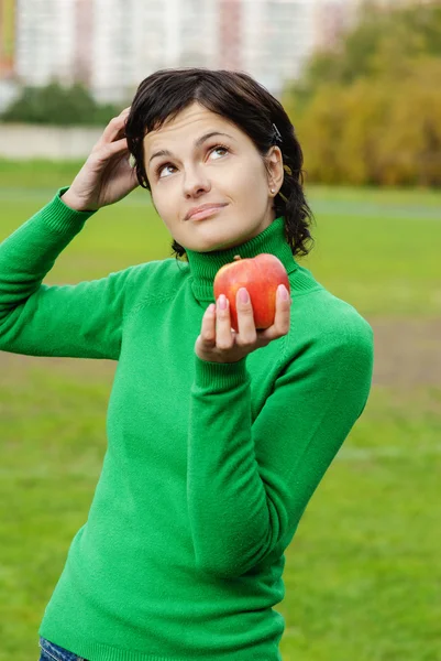 Smiling cute woman bites ripe apple — Stock Photo, Image