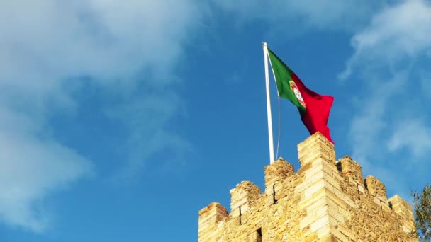 サン・ホルヘ城のポルトガル国旗は、リスボンとテージョ川のポルトガルの歴史的中心部を見下ろす指揮の丘の頂上を占めるムーア人の城です。. — ストック動画