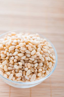 Bambu masa örtüsünün üzerinde kabuklu çam fıstığı olan cam kase..