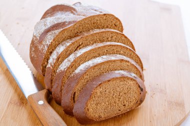 Koyu çavdar ekmeği ahşap bir tahtanın üzerinde yatıyor..