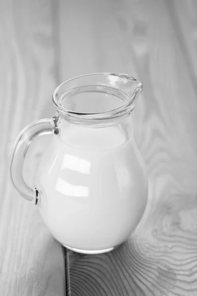 有新鲜牛奶的玻璃瓶放在木制桌子上 — 图库照片