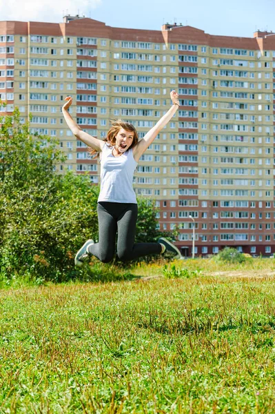 若い美しい女性が緑の松林の背景にジャンプします — ストック写真