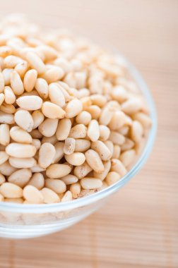 Bambu masa örtüsünün üzerinde kabuklu çam fıstığı olan cam kase..