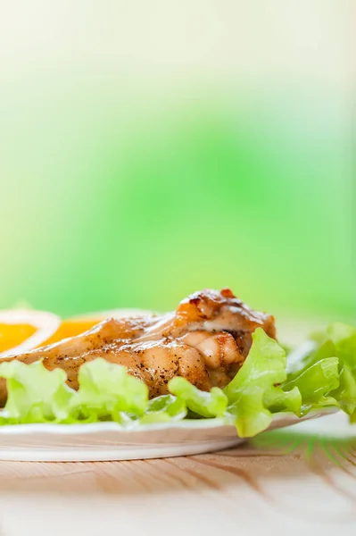 鶏の身と刻んだリングを炒めた 黄色のコショウは 木製のテーブルの上に皿の上に緑のサラダに横たわっています — ストック写真