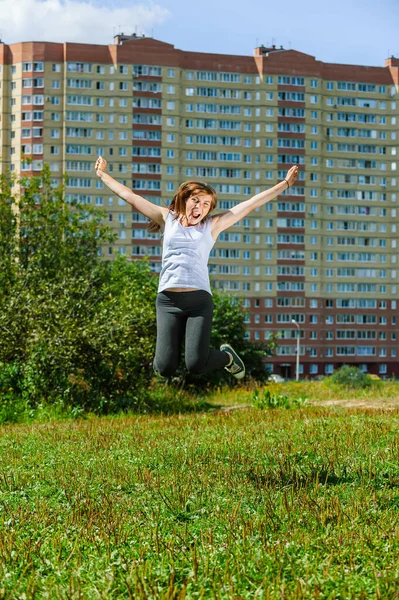 Young beautiful woman jumps up on the background of a green pine forest.