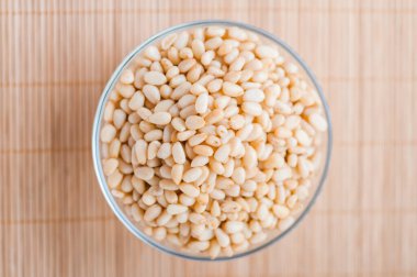 Bambu masa örtüsünün üzerinde kabuklu çam fıstığı olan cam kase..