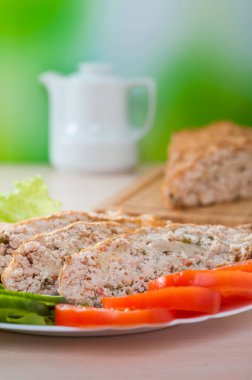 Sebzeli, salatalıklı, domatesli, marullu bir rulo köfte. Süt testisinin arka planında.