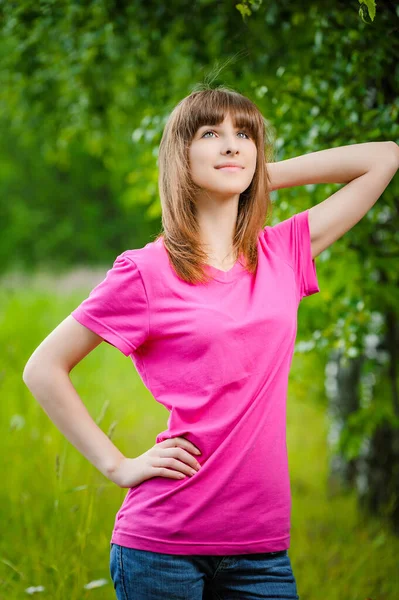 夏の緑のダウンタウンの背景に赤いブラウスに美しい若いブロンドの女性の肖像画 — ストック写真