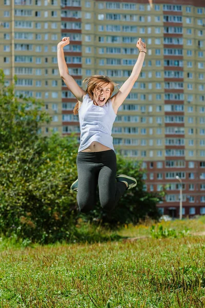 若い美しい女性が緑の松林の背景にジャンプします — ストック写真