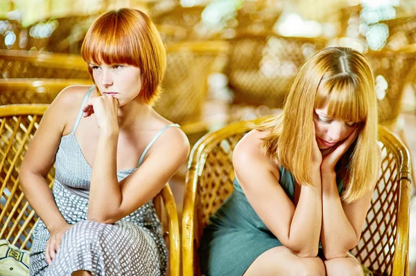 两个悲伤的年轻女子在一间有柳条椅的大房间的后面互相争吵着 — 图库照片