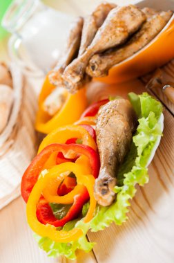 Tahta masaya karşı sebzeli tavuk budu (Bulgar biberi, marul).