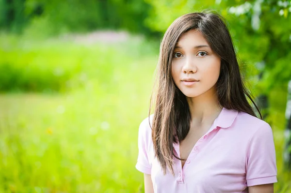 緑色の背景に濃い髪とピンクのブラウスを持つアジアの外観の美しい若い女性夏の自然 — ストック写真