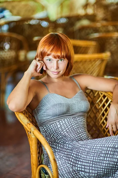 Beautiful Red Haired Young Woman Sits Woven Chair Talking Mobile — Stock Fotó