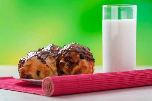 白いプレートにレーズンとチョコレートで飾られたカップケーキ 牛乳の背景のガラス緑の屋外 木製のテーブル — ストック写真