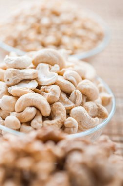 Cevizli üç cam kase, beyaz susam tohumu ve bambu peçetede kaju fıstığı..