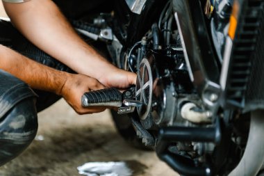 Araba tamircisi motosikletin motorunu tamir ediyor..