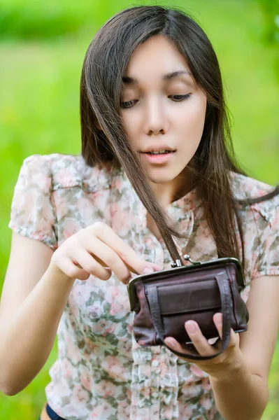 若いです可愛いです驚きアジアの女性とともに長いです黒髪チェック彼女の財布で夏緑の都市公園 — ストック写真