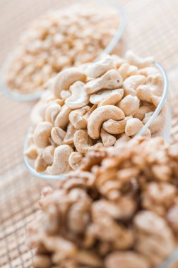 Cevizli üç cam kase, beyaz susam tohumu ve bambu peçetede kaju fıstığı..