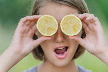 Genç, güzel, gülen bir kadın, yeşil parkta iki limon kupası tutuyor..