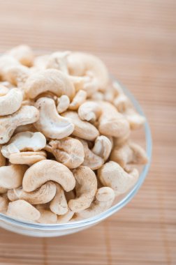 Bambu masa örtüsünün üzerinde kabuklu fındıklı cam kase..