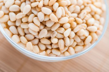 Bambu masa örtüsünün üzerinde kabuklu çam fıstığı olan cam kase..