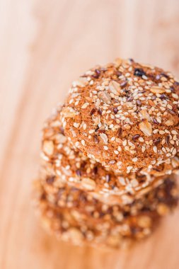 Lezzetli yulaf ezmeli kurabiyeler, ayçiçeği tohumları serpiştirilmiş ahşap masa üzerinde susam tohumları.