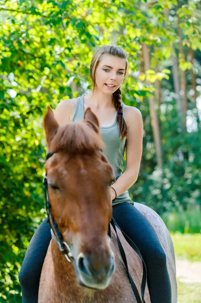 緑の夏の自然を背景に私たちに乗って雄牛に乗っている若いかなり笑顔の女性 — ストック写真