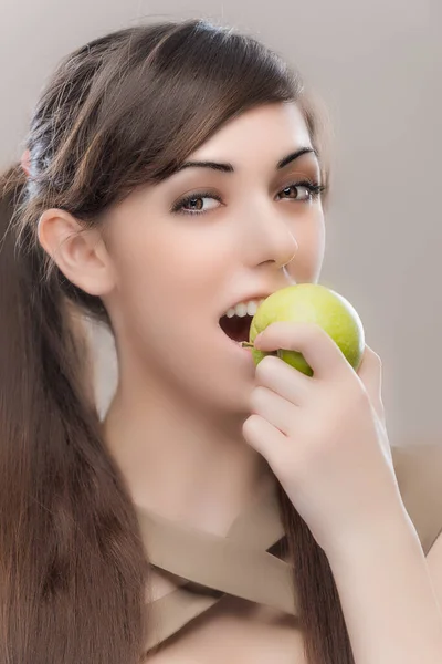 Młoda Piękna Kobieta Ciemnymi Długimi Włosami Gryzie Zielone Jabłko Szarym — Zdjęcie stockowe