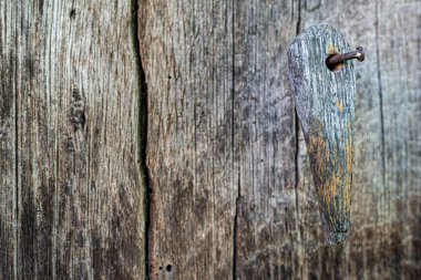 Eski çürük bir kapıya çakılmış paslı bir çiviye asılı tahta bir sürgü..