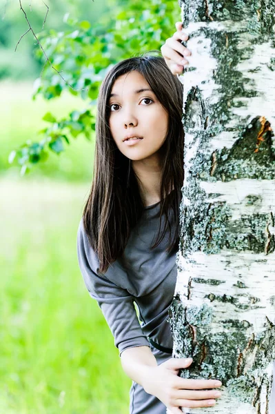 美丽的年轻女子 相貌像亚洲人 站在白桦树旁 背景是夏日的绿色 — 图库照片
