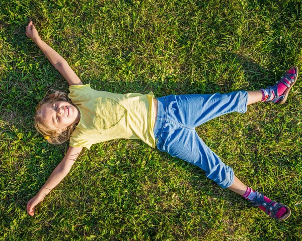 Bonita Niña Pantalones Azules Una Camiseta Amarilla Está Acostada Césped — Foto de Stock