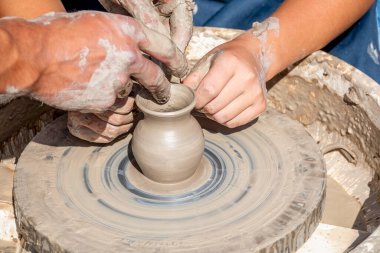 Çömlek ustası öğrenciyi kilden küçük bir sürahi yapmaya teşvik ediyor. Kil tabak yapmak için bir pikap. El yapımı..