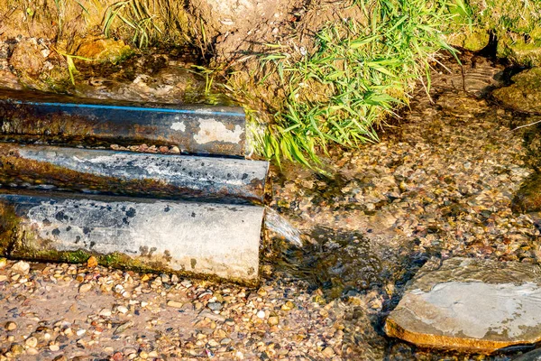 Вода Вытекает Источника Помощью Труб Почву Солнечный Летний День — стоковое фото