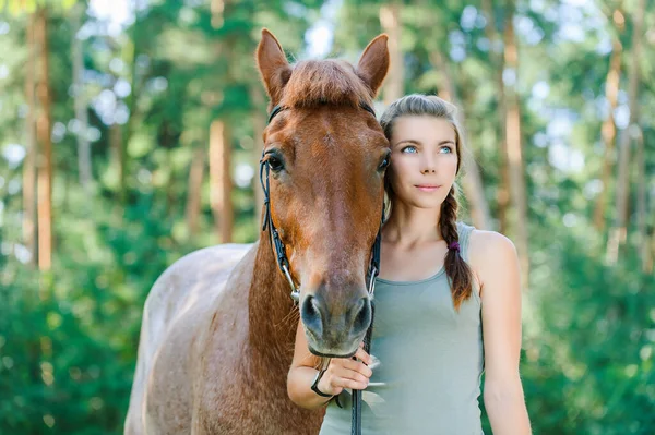 緑の夏の自然と松の森に対して壮大な鞍馬の横に若い美しい女性の笑顔 — ストック写真