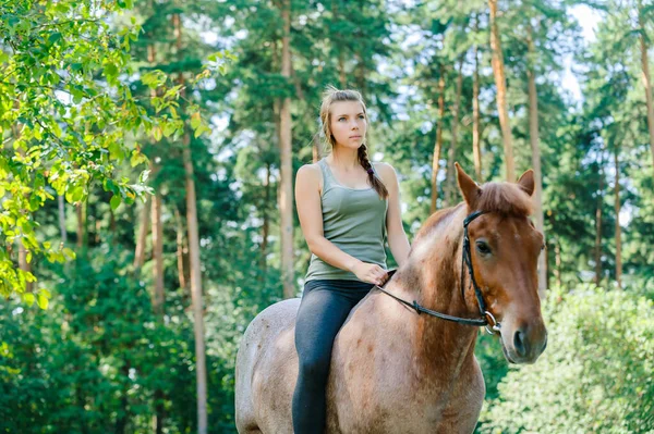 緑の夏の自然を背景に私たちに乗って雄牛に乗っている若いかなり笑顔の女性 — ストック写真