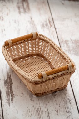 Tahta saplı dikdörtgen hasır sepet masanın üzerinde duruyor..