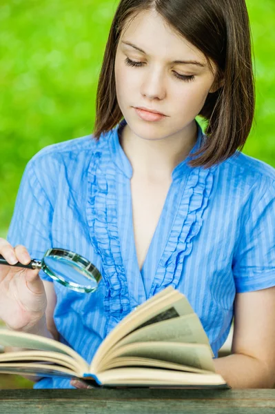 Молодая женщина крупным планом читает книги увеличитель — стоковое фото