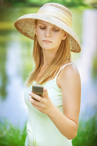 Flicka i stråhatt med telefon — Stockfoto