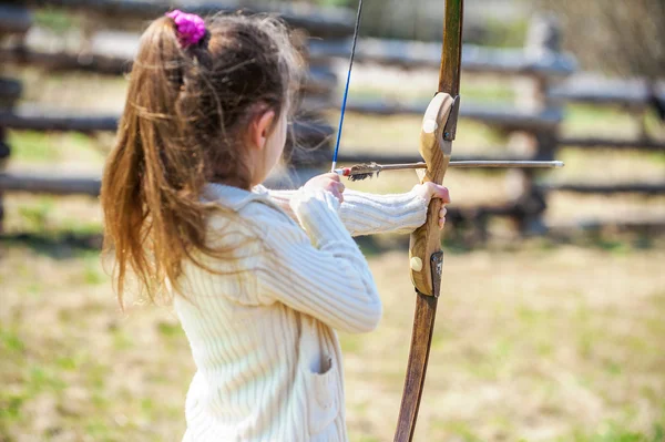 Маленькая девочка стреляет в лук — стоковое фото