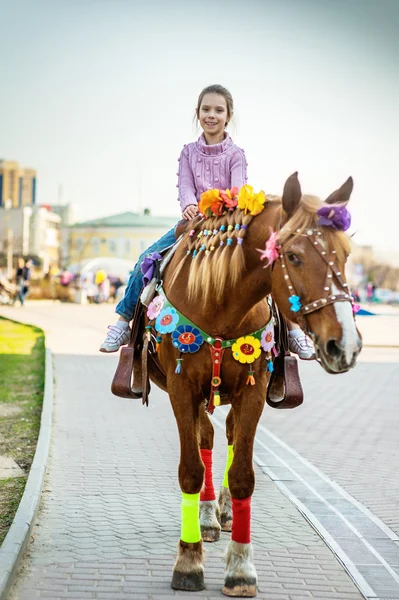 Little girl riding festive horse — Stock Photo, Image
