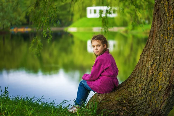 어린 소녀가 앉아 호수 근처 — 스톡 사진