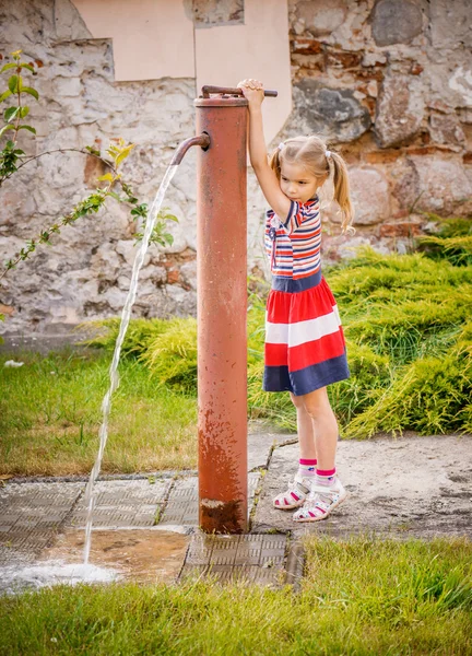 Küçük kız su musluğu açar — Stok fotoğraf
