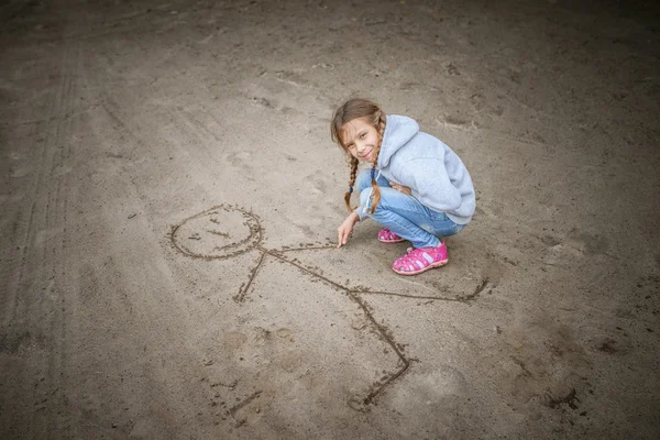 Pequena areia menina desenha homem engraçado — Fotografia de Stock