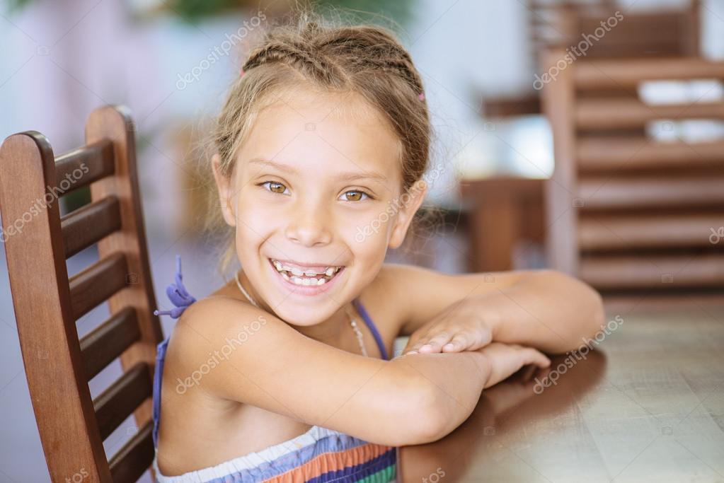 Little girl sitting at table — Stock Photo © BestPhotoStudio 54217617