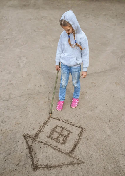 Little girl draws in the sand — Stock Photo, Image