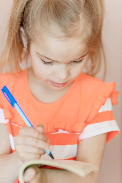 Niña escribe pluma en cuaderno — Foto de Stock