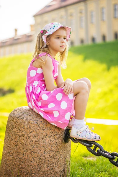 Маленькая грустная девочка сидит на скале — стоковое фото