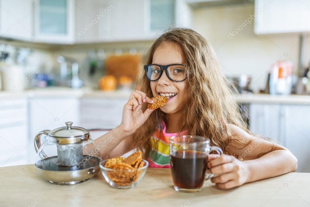 Little girl eating cookies and drinking tea