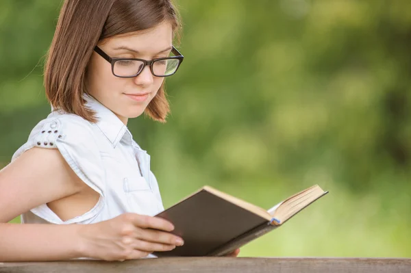 Ragazza carina che indossa occhiali da vista lettura libro poco interessante — Foto Stock