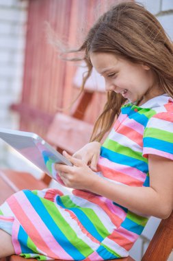 Tablet PC'de oynarken küçük gülümseyen kız